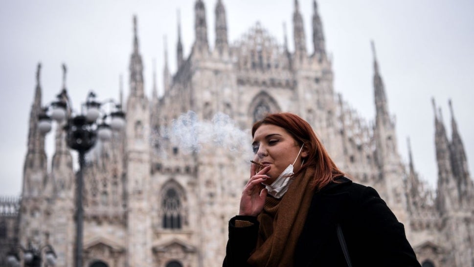 A woman smokes a cigarette on Piazza del Duomo in Milan on January 19, 2021 