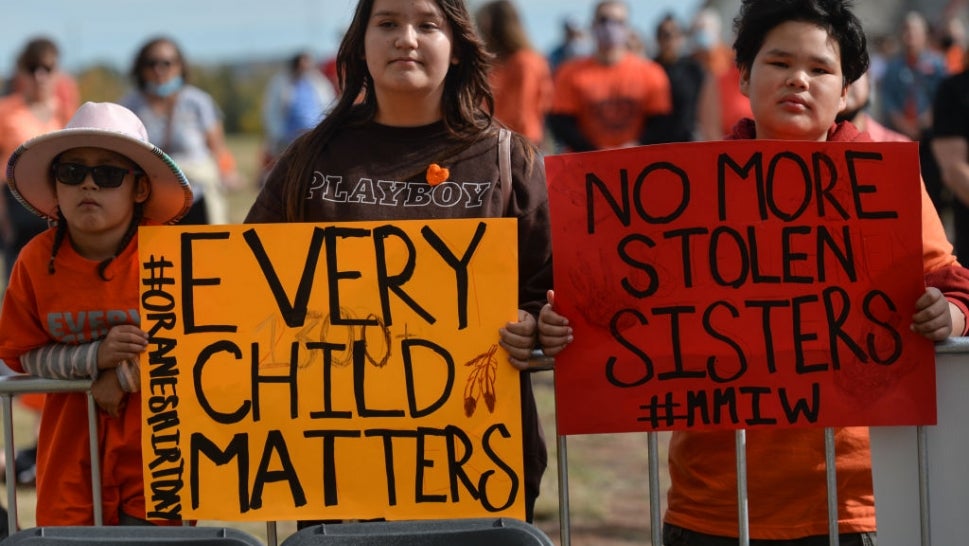 Demonstrators hold up signs on the country's first Orange Shirt Day.