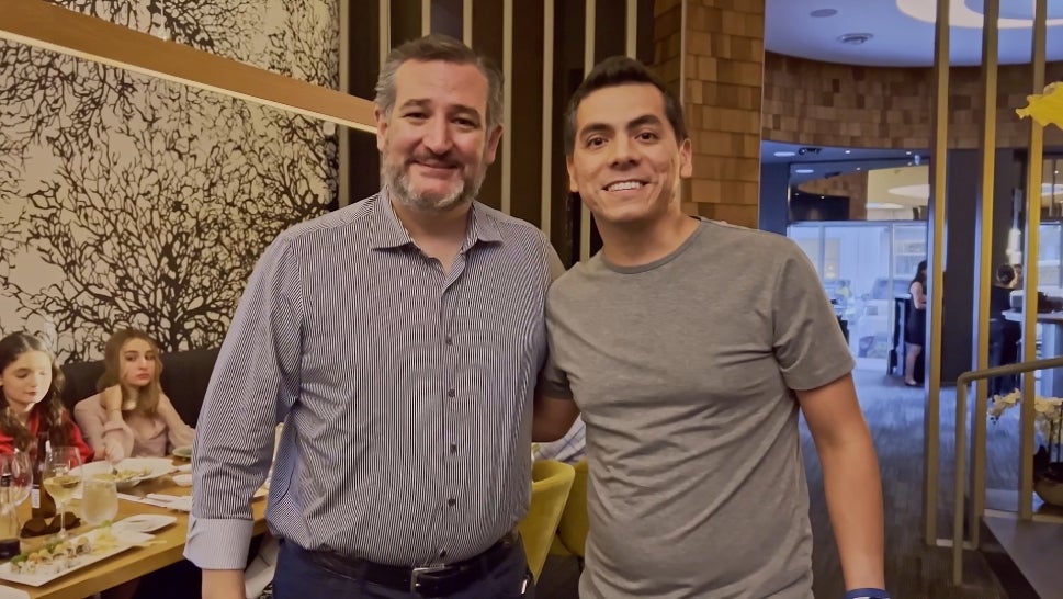 An activist pretends to take a photo with Ted Cruz before confronting the Texas senator on his views on gun rights in the wake of the school shooting at Uvalde.