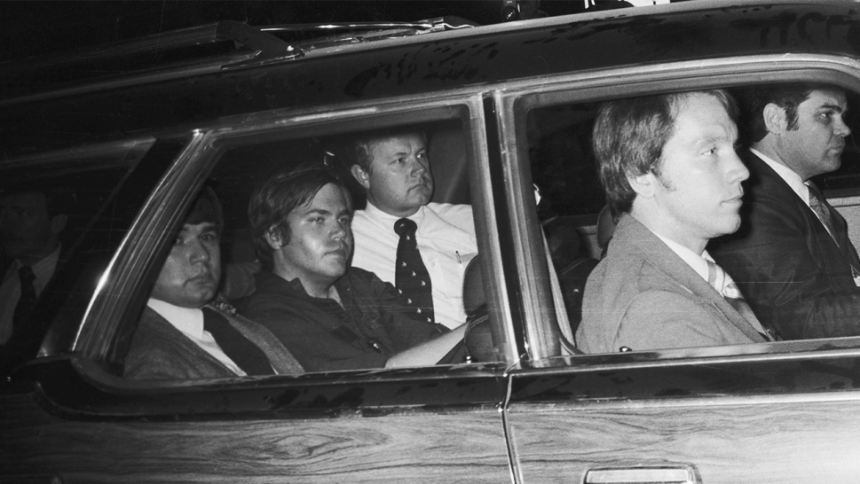 John Hinckley Jr being driven away from U.S. District Court seated around agents.
