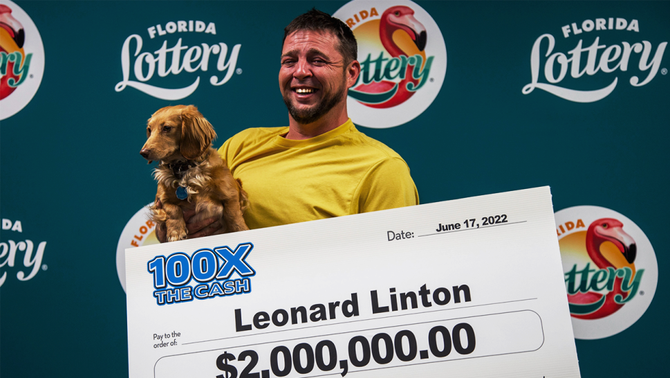 Linton holding his dachshund, Ivy, and a large $2 Million check