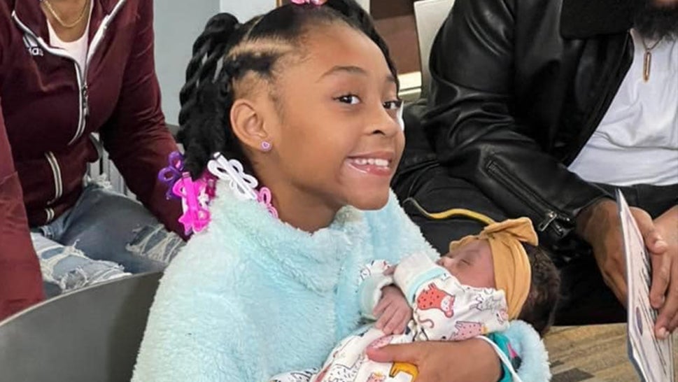 Miracle holding her newborn baby sister