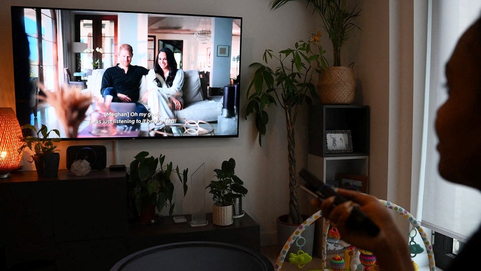A viewer watches the 'Harry & Meghan' Netflix docuseries at home.