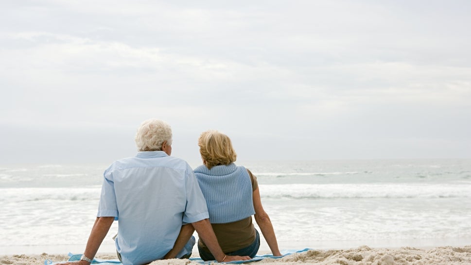Senior couple sitting on a beach - stock photo