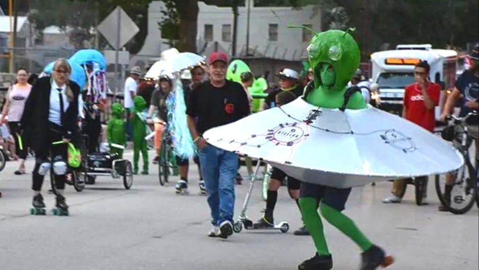 parade featuring someone in alien costume in roller skates