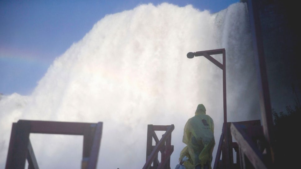 A visitor walks near the American Falls while taking the Cave of the Winds tour in Niagara Falls, New York, U.S