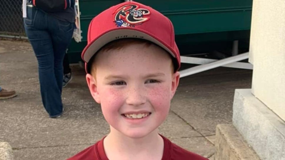 Eli Hill, 8, white boy smiling wearing red baseball cap