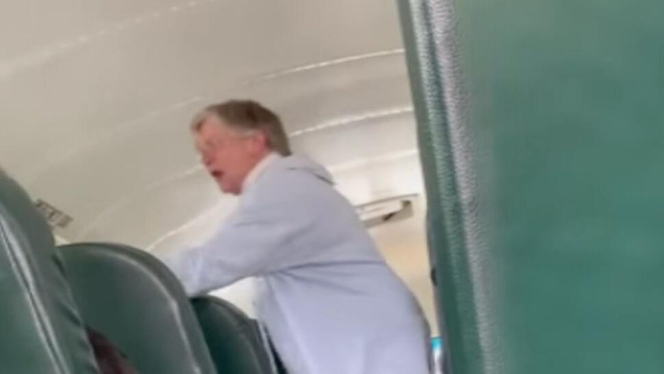 68 year old woman wearing blue sweater pointing at student in bus seat