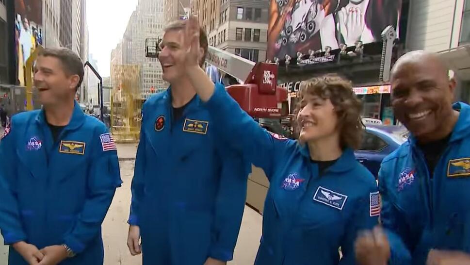 4 astronauts Victor Glover, Christina Hammock Koch, Reid Wiseman and Canadian astronaut Jeremy Hansen stand in Times Square waving at people