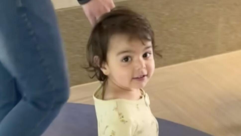 2-year-old Mira smiling, brown hair, yellow clothes