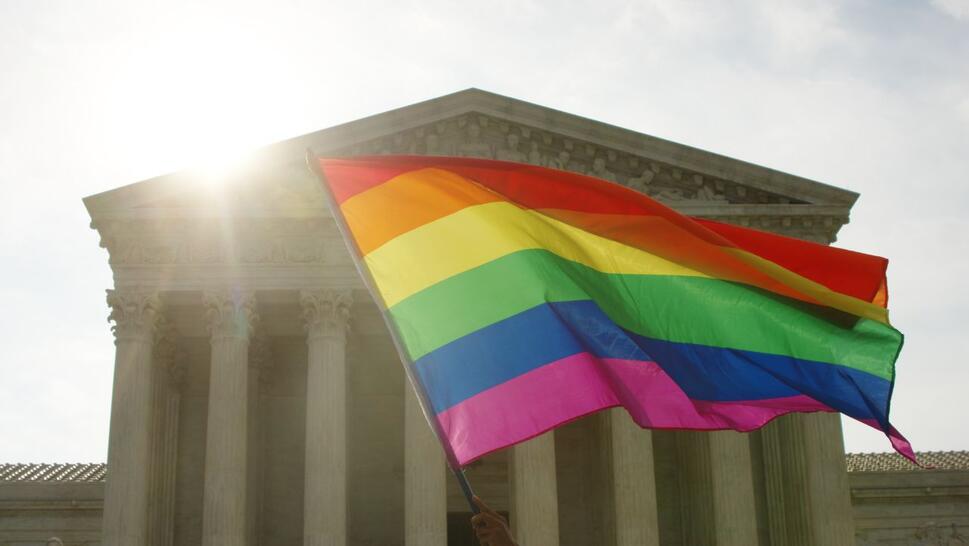 An LGBTQ+ supporter waves a rainbow flag at the United States Supreme Court on the morning of the landmark Obergefell decision legalizing gay marriage nationwide.