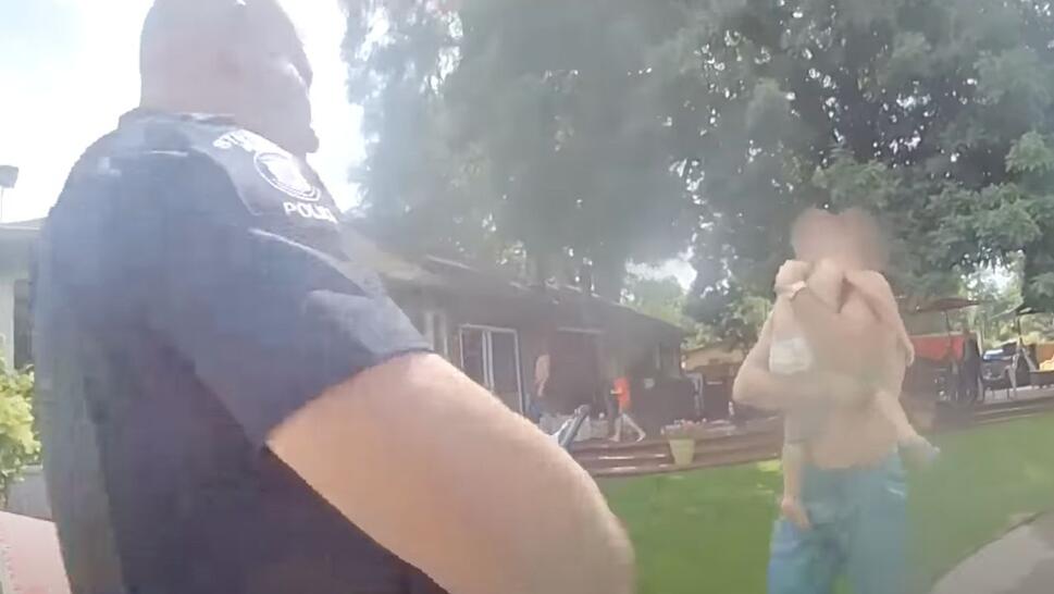 dad holding his toddler son walking towards police officer