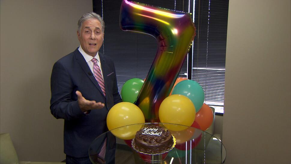 Jim Moret standing next to mylar balloons