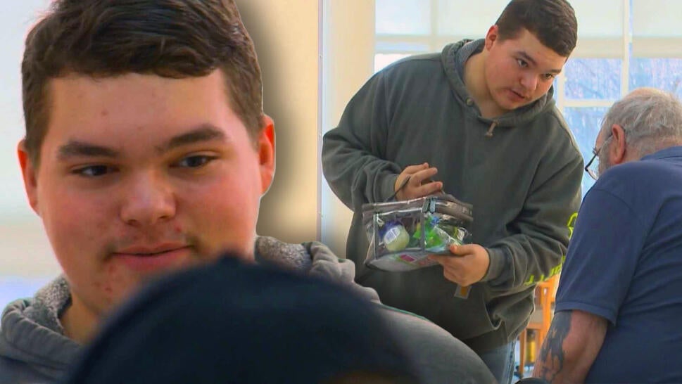 Close up of teen speaking to veteran / Teen handing a clear bag of toiletries to a veteran in a wheelchair