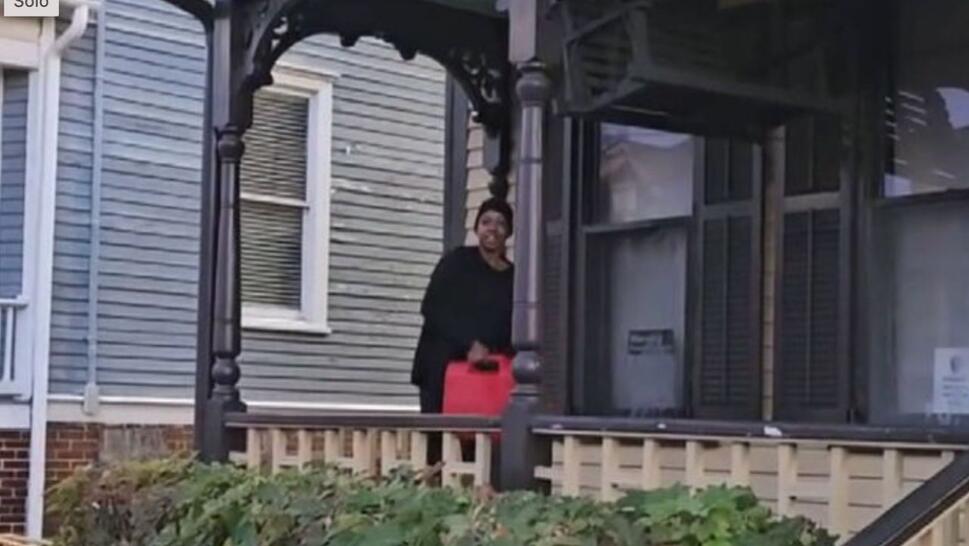 woman wearing all black holding gasoline tank while standing on porch of Dr. Martin Luther King Jr.'s birth home