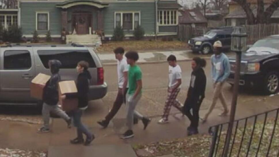 5 teens walking behind 2 kids holding boxes
