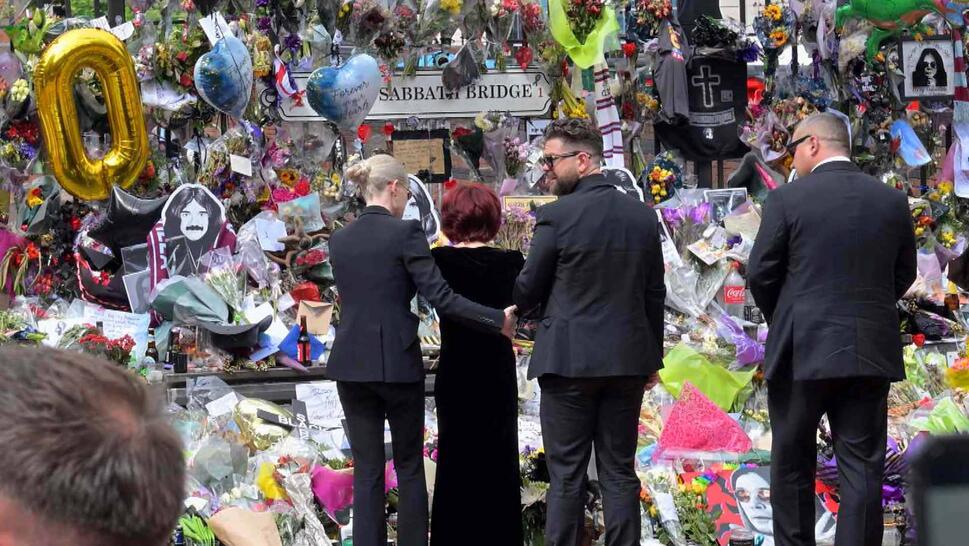 Ozzy Osbourne's widow mourning in front of a large display of memorabilia 