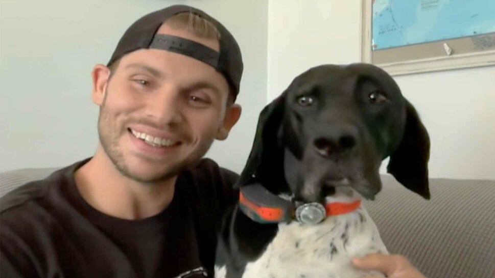 Man smiling next to his medium sized dog