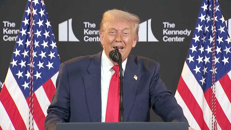 President Donald Trump speaking at a podium in front of a step-and-repeat for The Kennedy Center