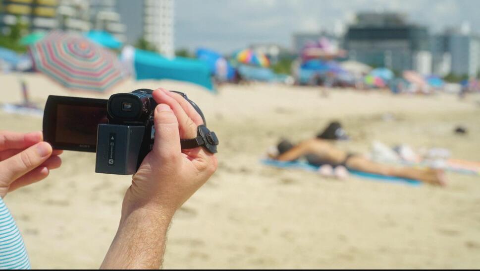 Person recording video of woman on beach