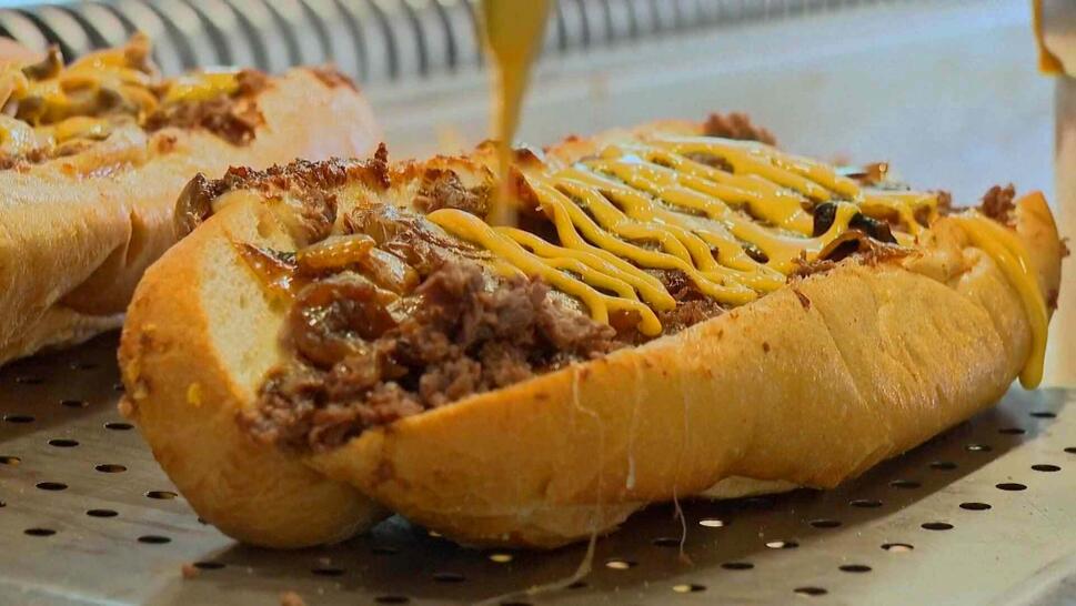 Cheese poured onto steak sandwich