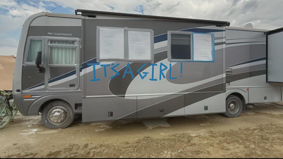 Camper van at Burning Man with "It's a Girl!" written on the side