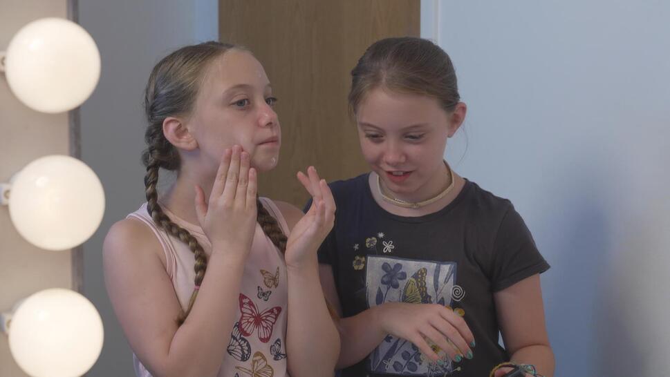 Two girls applying face cream in a mirror
