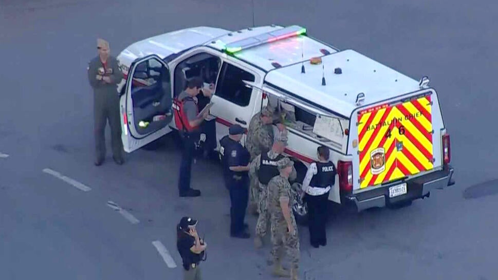 People in military fatigues standing around an emergency vehicle on a school campus