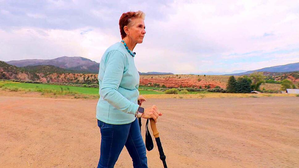 Woman walking with walking sticks along a dirt road