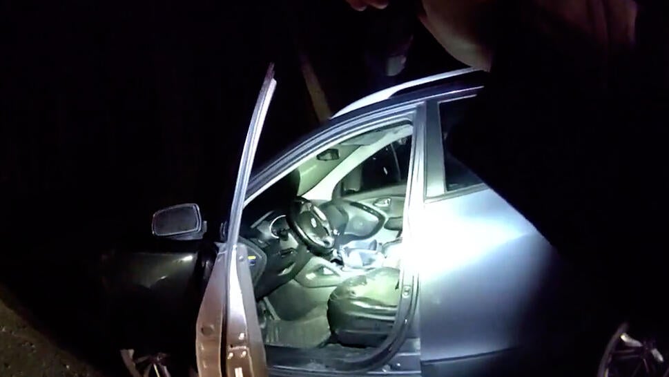 Police officer shines flashlight into car 