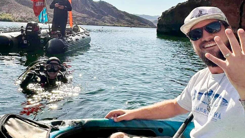 Man in kayak shows off wedding ring near scuba diver