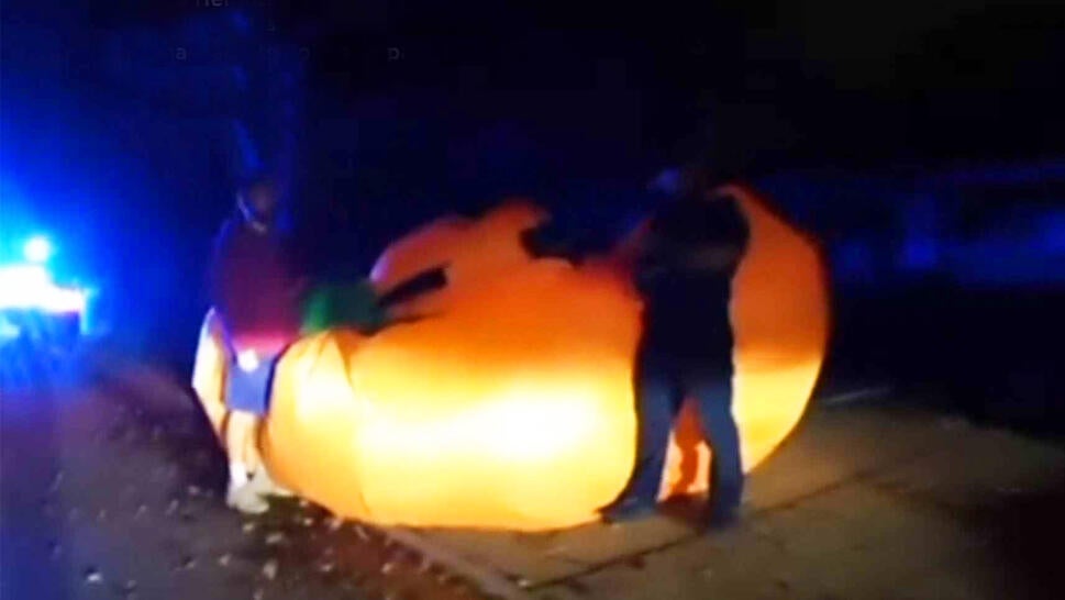 Two people standing with giant inflatable pumpkin