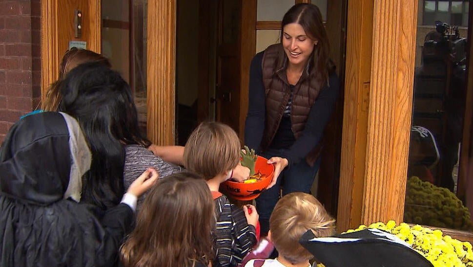 Woman hands out candy to Halloween trick-or-treaters