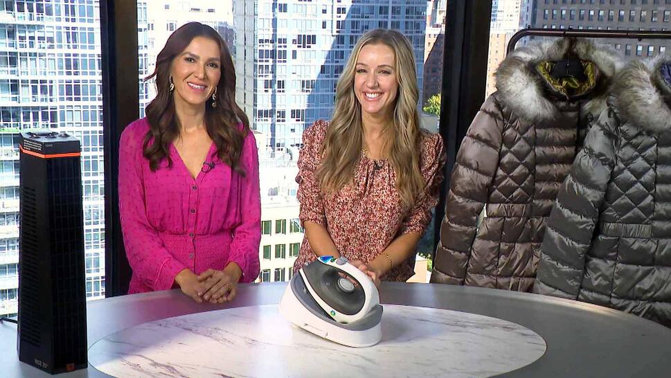 Two women standing behind a table displaying a Heater, Steam Iron, Puffer