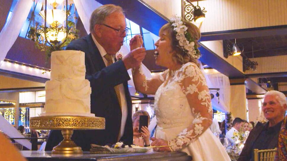 Couple kissing next to a 3-tier wedding cake