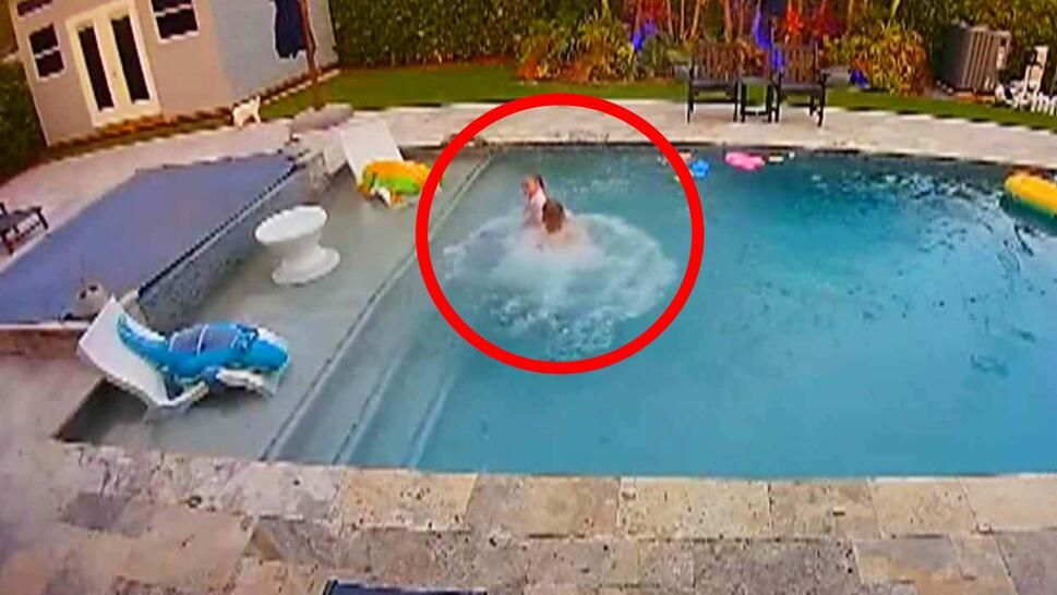 Surveillance footage of a swimming pool with a man holding a child above water, in a red circle