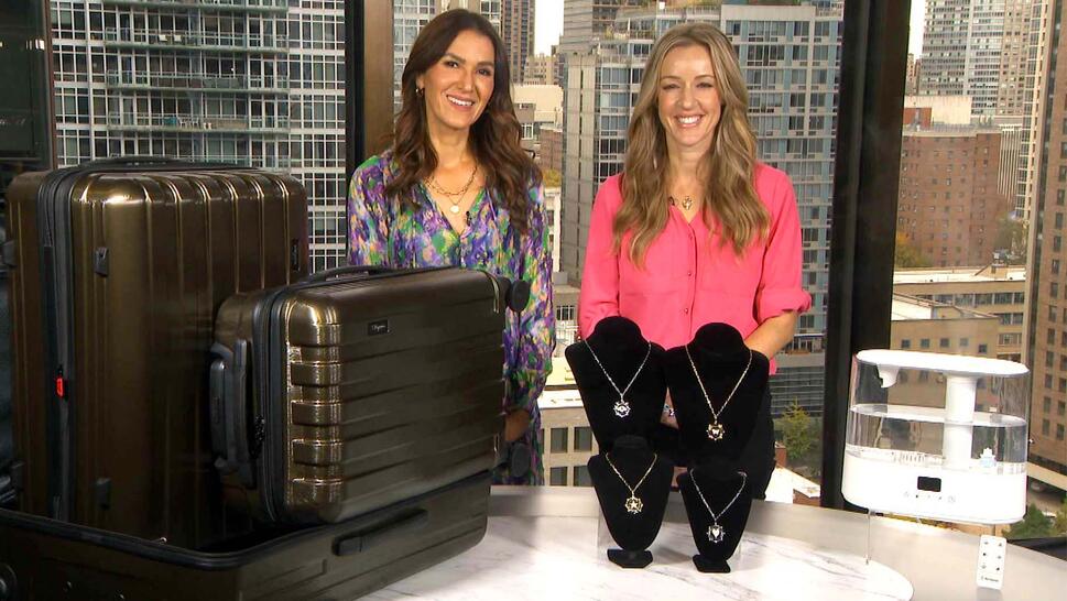Two women standing behind a table displaying Luggage Set, Necklace, Humidifier