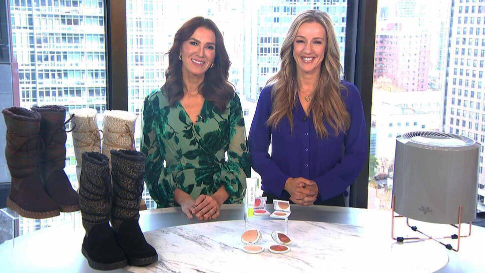 Two women standing behind a table displaying Boots, Makeup Set, Air Purifier