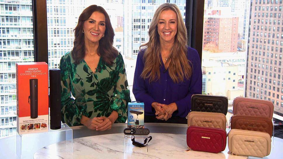 Two women standing behind a table displaying a Precision Cooker, Luggage Scale, Crossbody