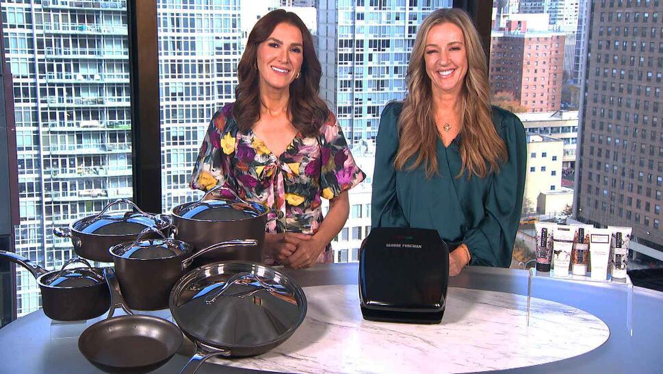 Two women standing behind a table displaying a Cookware Set, Indoor Grill, Hand Creams