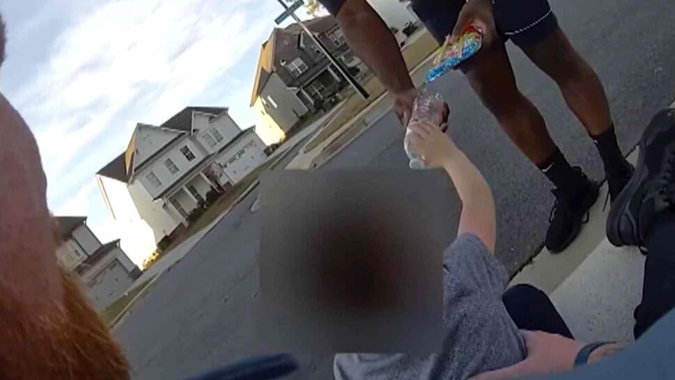 Little boy takes bottle of water from adult