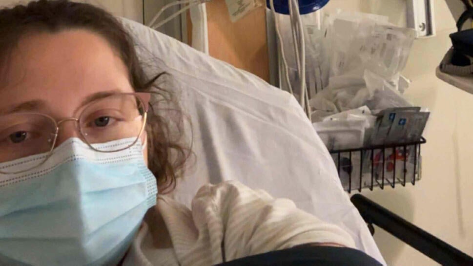 Woman wearing a surgical mask in a hospital bed