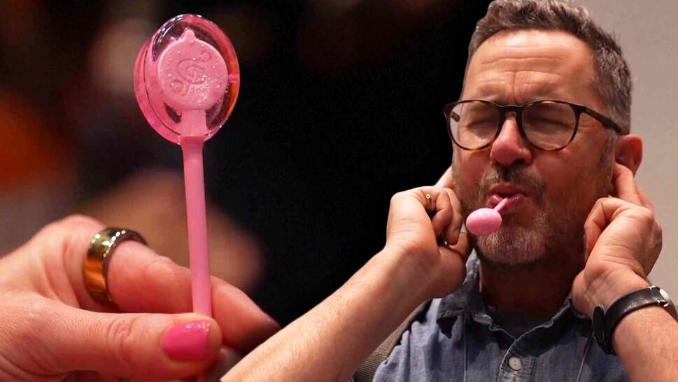High-tech lollipop, man plugging ears with lollipop in mouth