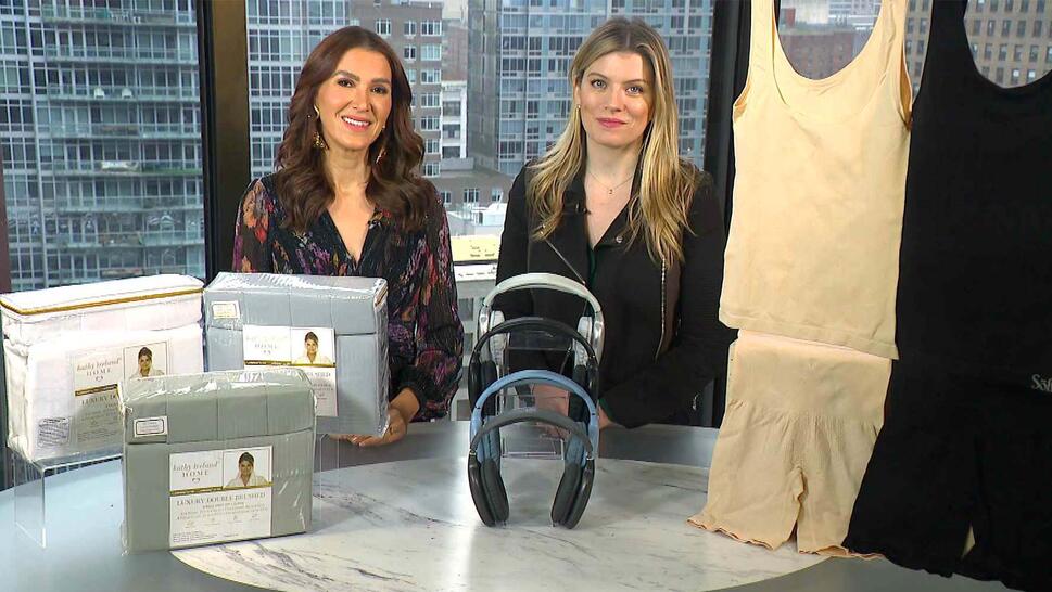 Two women standing behind a table displaying a Sheet Set, Headphones, Compression Tank Tops Or Shorts