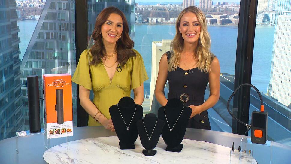 Two women standing behind a table displaying a Precision Cooker, Necklace, Tire Inflator
