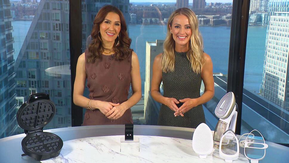 Two women standing behind a table displaying a Waffle Maker, Stud Earrings, Iron