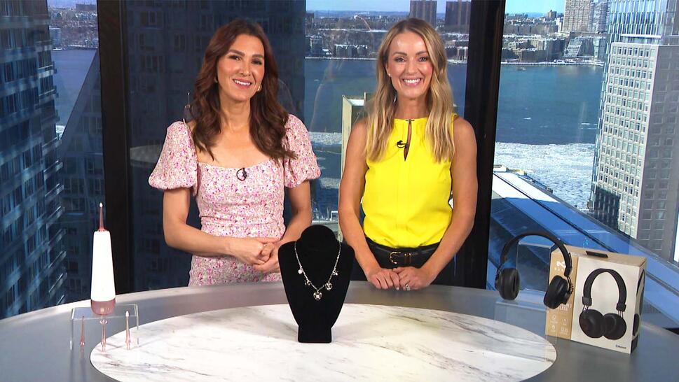 Two women standing behind a table displaying a Water Flosser, Necklace, Headphones