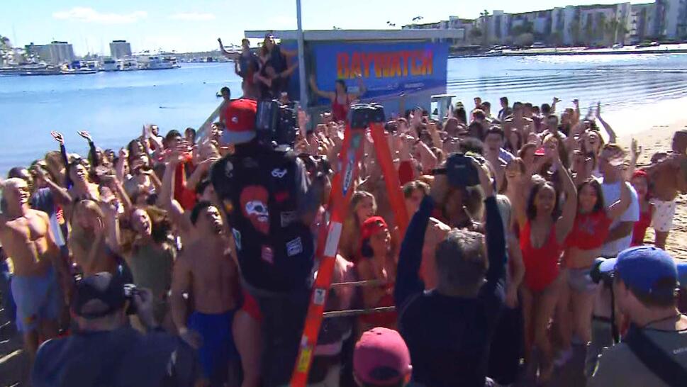 Large crowd of people cheering for a photo taken by a man on a ladder 