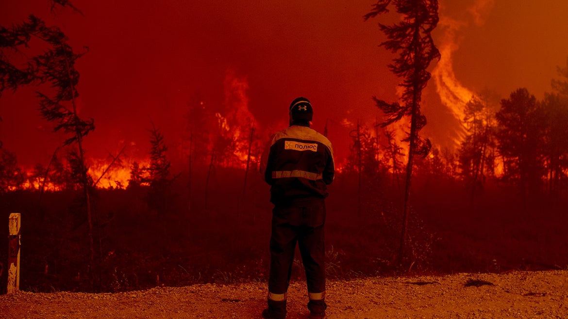 A firefighter stands in front of the forest fires raging in Yakutia, Siberia.