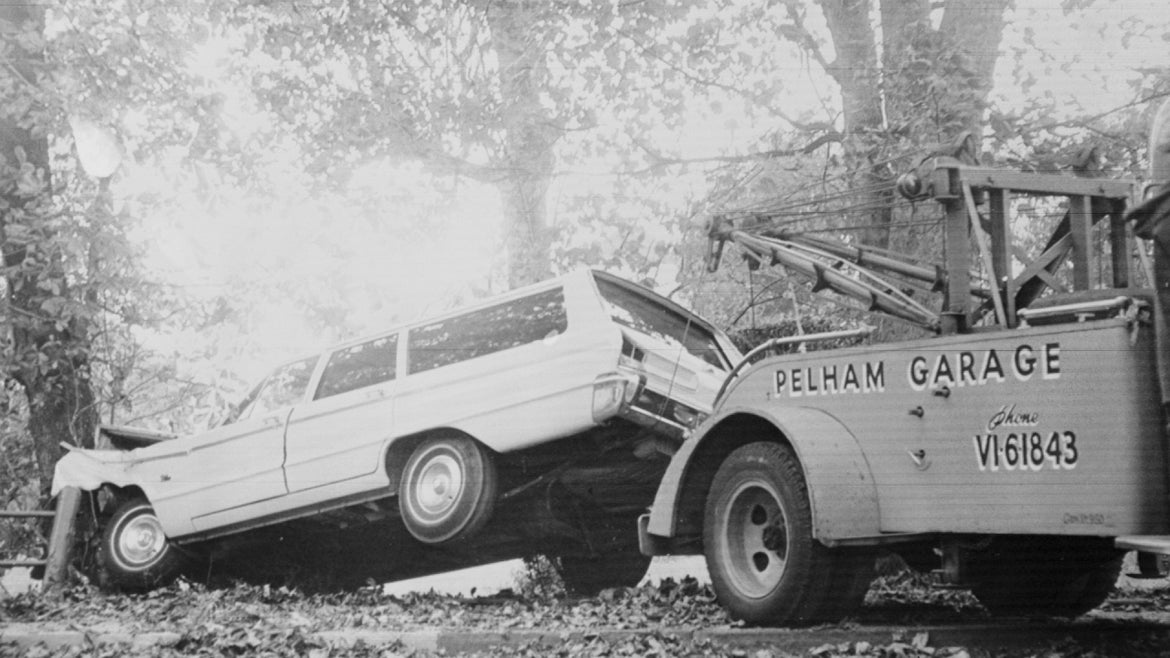 Newport, R.I.: Tow truck prepares to haul away station wagon driven by Doris Duke which fatally crashed Eduardo Tirella. 